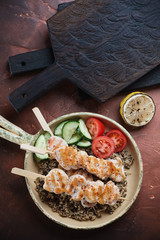 Serving pan with chicken skewers, quinoa and fresh vegetables, vertical shot, above view