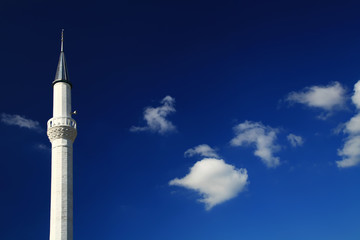 Obraz premium A tall white minaret of a Muslim mosque against the sky.
