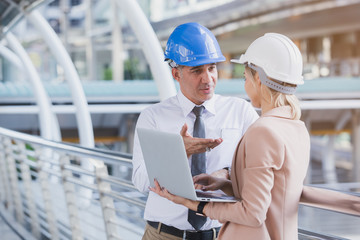 Senior leader engineer and personnel woman talking and planning work with laptop in hand, architect teamwork.