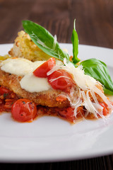 Soft focus photo of roasted chicken fillet with tomato cherry, parmesan and crouton on dark wooden background