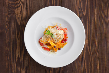Top voew of fried turkey meat with roasted tomato and bell pepper served with parmesan, cranberry and orange balsamic sauce on dark wooden background