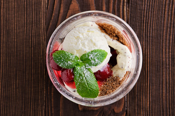Delicious tiramisu dessert with cherry in rustic pot on dark wooden background
