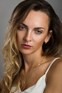 A delightful elegant young woman with long blonde hair in a light white blouse on the straps
