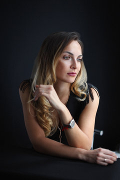 A very sexual delightful young woman with long blonde hair in a small black dress with no sleeves