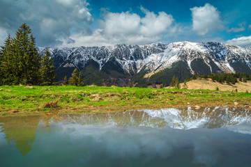 Alpine spring landscape with snowy mountains in background, Transylvania, Romania
