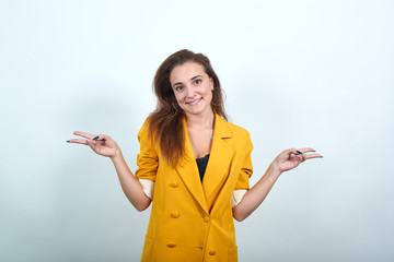 Cheerful young woman in yellow jacket isolated on gray background in studio, showing victory...