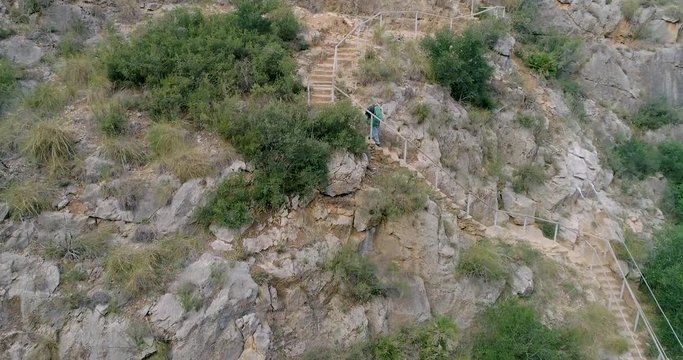 Persona mayor senderista bajando escalones en monta&ntilde;a de piedra vertical