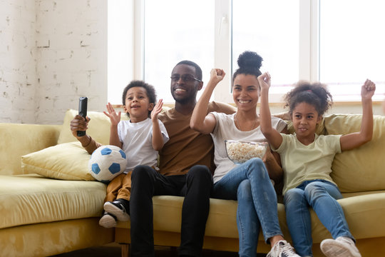 Happy biracial family with kids watch football at home together