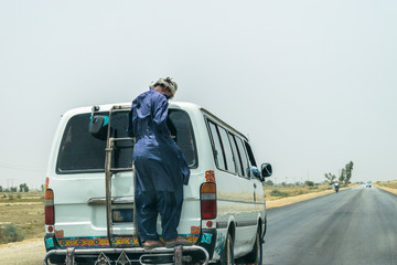 a passenger is hanging and traveling behind a mini van on a speedy highway at high risk of accident cause of transportation crises 
