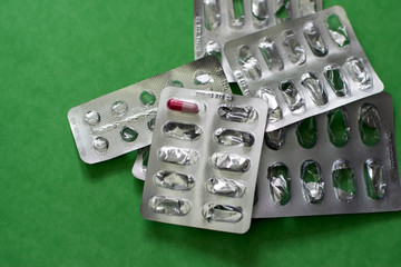 Pack of pills on green background. One tablet in the pack.