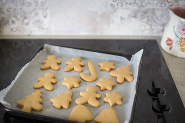 Homemade baked festive Christmas shaped cookies cooling on the top of the oven 