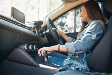 Fototapeta na wymiar Closeup image a female driver shifting automatic gear stick while driving car