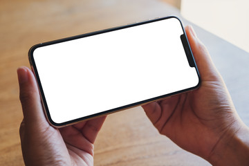 Mockup image of a hand holding a black mobile phone with blank white desktop screen