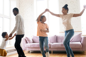 Obraz premium Excited biracial family with kids have fun dancing at home