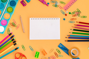 School or office orange desk table background. Blank sheet of paper and office accessories. Back to school. 