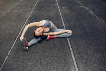 Beautiful girl at the stadium. Sports girl in a sportswear. Lady doing yoga