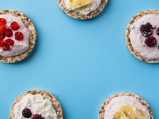 Some Crispbread with cottage cheese and fruit on a blue background. In the middle place for text
