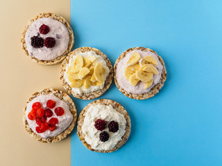 Dessert on blue and yellow background. Crispbread, cottage cheese and fruit