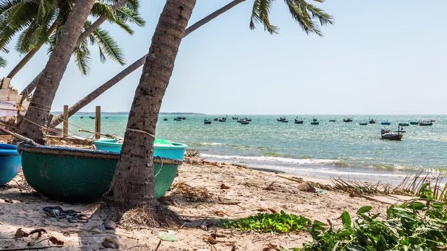 Coracles boat on the beach with fishing boats anchored at sea in background, Mui Ne, Vietnam time lapse