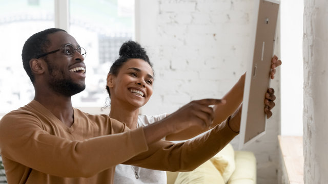 Excited biracial couple decorating new home together