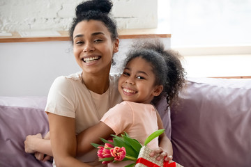 Happy african American mom and daughter hug celebrating birthday