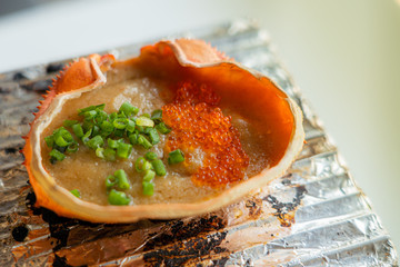 Kani miso. Japanese Kani Miso crabmeat with soybean paste grilled in crab shell at traditional Japanese restaurant. Close up and selective focus. Chacoal grill.