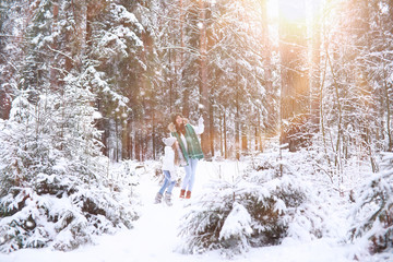 Young family for a walk. Mom and daughter are walking in a winter park.