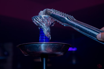 colocando con pinzas la piedra incandescente en la cachimba 