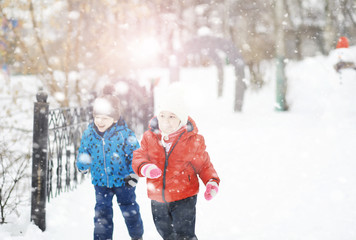 Children in the park in winter. Kids play with snow on the playground. They sculpt snowmen and slide down the hills.