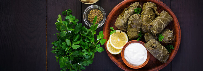 Dolma. Stuffed grape leaves with rice and meat on dark table. Middle eastern cuisine. Top view,...
