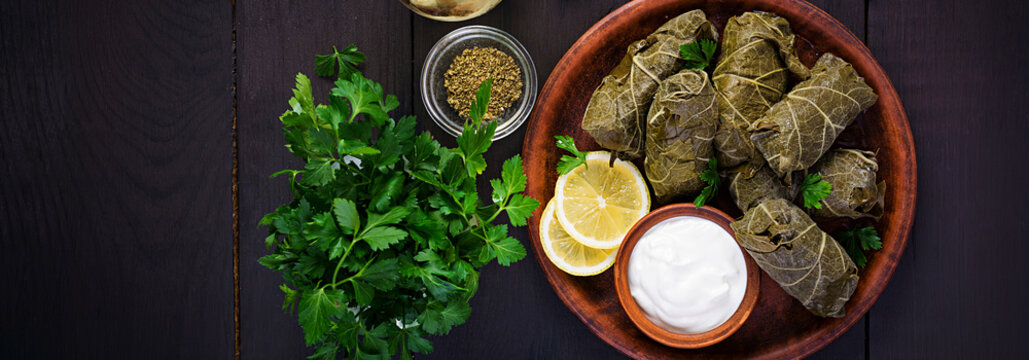 Dolma. Stuffed grape leaves with rice and meat on dark table. Middle eastern cuisine. Top view, overhead, banner
