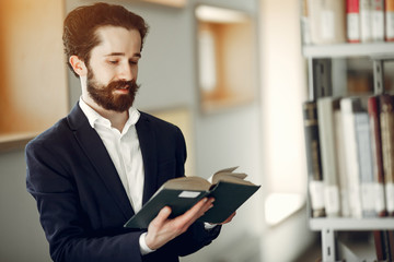 Man in a library. Guy in a black suit. Student with a books.