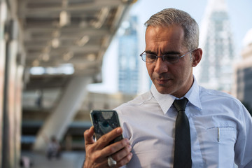 50s American businessman check smartphone in city