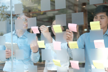 business people working planning discussing idea with sticky reminder note on glass wall