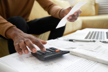 African American man calculating on machine accounting expenses
