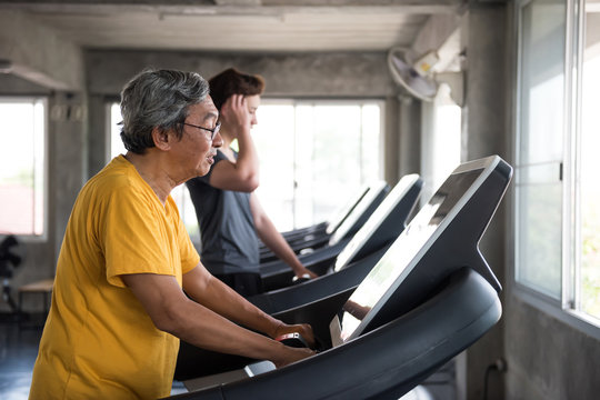 Senior and young men run on treadmill in gym