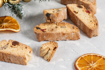 Traditional Italian biscotti or Cantuccini cookies with hazelnuts, almonds, walnuts on a gray background with slices of dried oranges and a Christmas tree. The concept of Christmas baking
