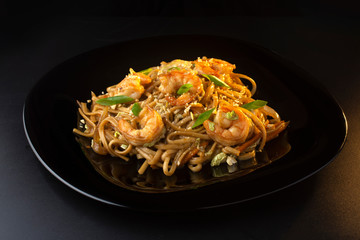 noodles with paste, shrimp and herbs on black plate