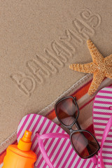 Fototapeta na wymiar Word BAHAMAS written in sand with beach accessories.
