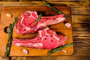 Raw ribeye steak, spices, rosemary and garlic on cutting board. Top view