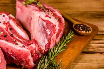 Raw pork ribs with spices and rosemary on a cutting board