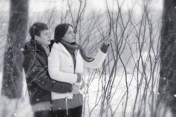 A loving couple on a winter walk. Man and woman on a date in the park in winter. Friends in a winter park