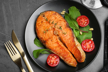 Delicious roasted fish served on grey table, flat lay