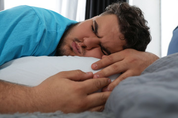 Fototapeta na wymiar Depressed overweight man hugging pillow on bed