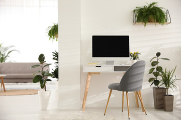 Modern workplace in room decorated with green potted plants. Home design © New Africa