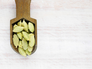 Spice Green cardamom (Elettaria cardamomum) in a scoop on a white wooden background with copy space