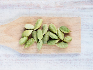 Spice Green cardamom (Elettaria cardamomum) on a spatula horizontally on a brown wooden background