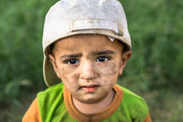 a cute smiling happy playing boy in garden his face and clothes are dirty 