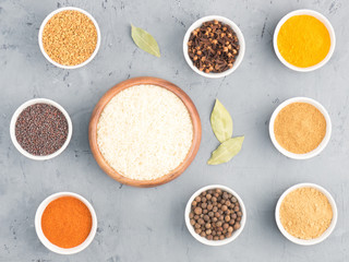 Rice, allspice, pepper chili, fenugreek, cloves, turmeric, masala, dry ginger, mustard seeds in bowls on black concrete background with copy space. Indian cuisine, ayurveda, naturopathy concept