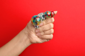 Woman squeezing colorful slime on red background, closeup. Antistress toy